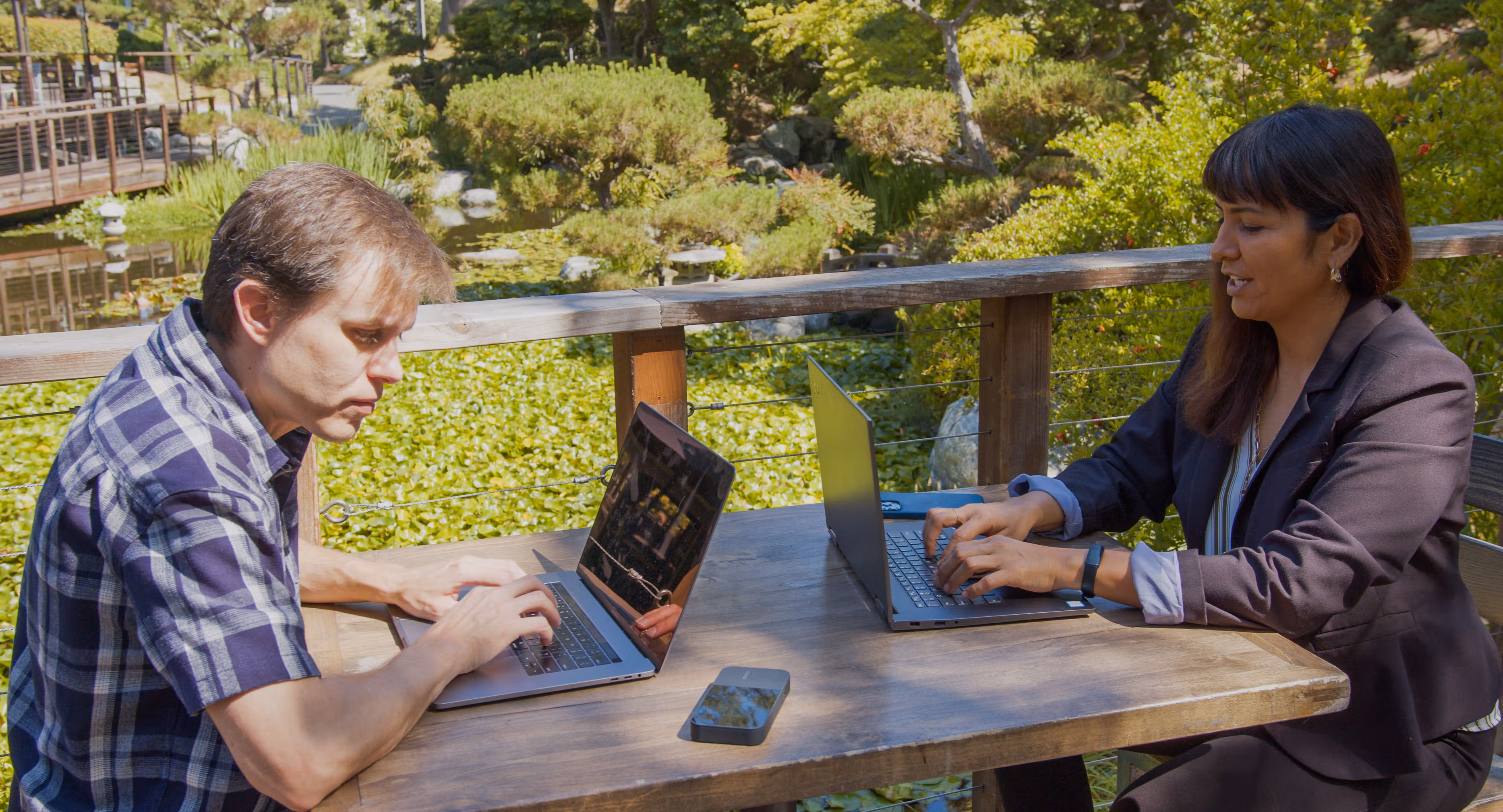 Two employees using a business-grade mobile hotspot outside to stay connected