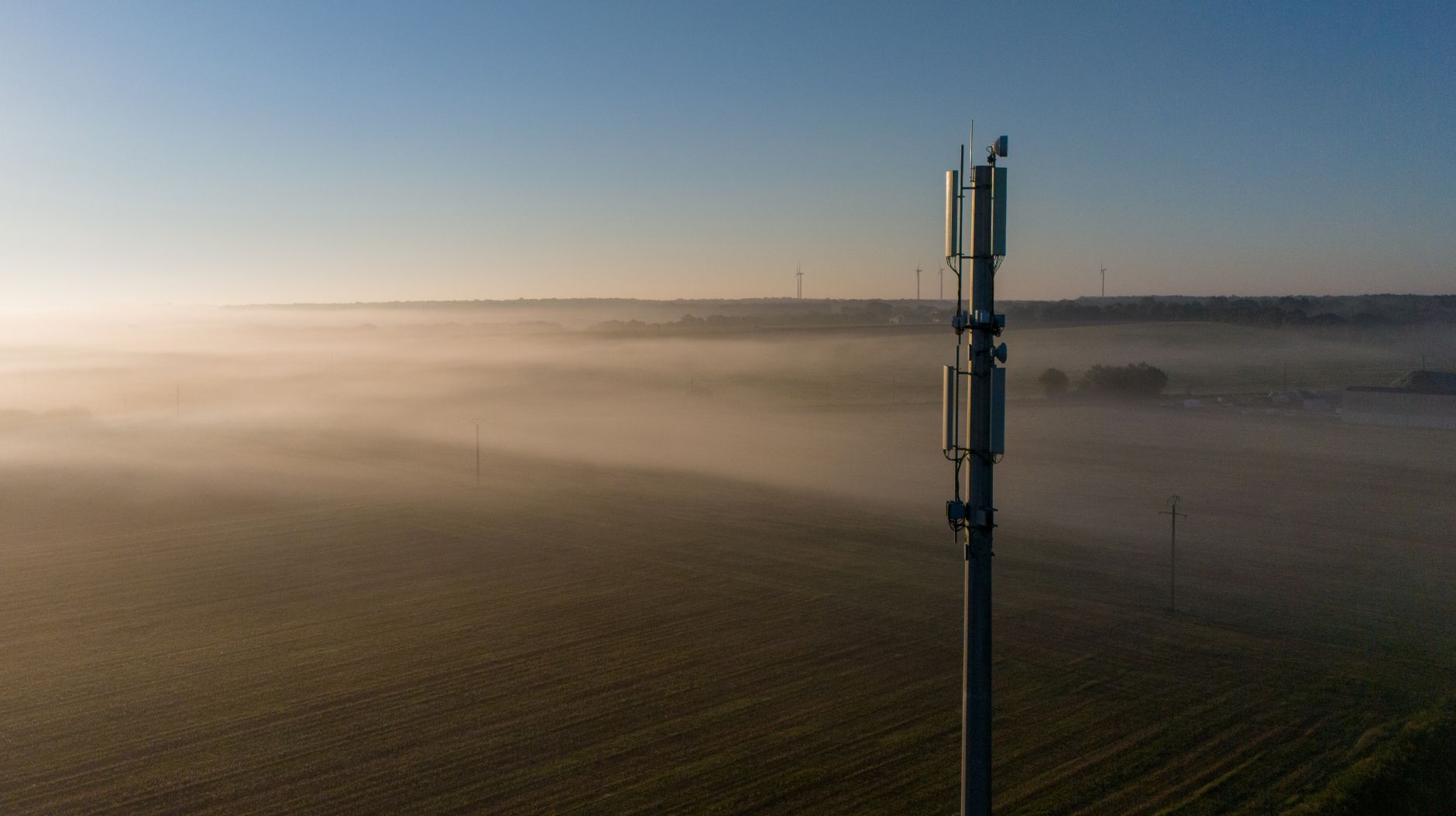 A 5g cell tower towering over a large field in a rural location to provide connectivity